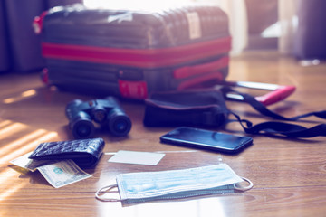 Medicine mask with blurry luggage , money, credit card, Binoculars, and travel equipment. Surgical masks with blurry hand sanitizer believed to help prevent the spread of infection like Coronavirus.