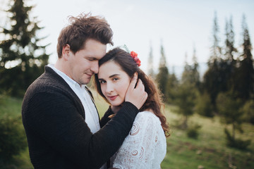 Wedding in the mountains. Young couple cuddling against the backdrop of the forest and mountains at sunset