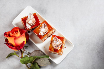 Layered cakes with rose on a white marmorean table.