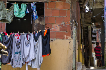 Clothes hung up to dry on clothesline in front of a rundown bare house in Santa Marta favela in Rio...