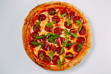 italian pizza with mozzarella and salami with arugula isolated on a white background