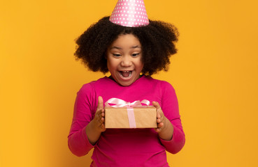Birthday Surprise. Overjoyed Little Black Girl In Party Hat Holding Gift