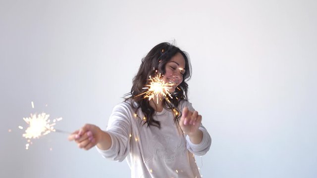 Beautiful brunette celebrating with sparkler and bengal fire. Close up. slow motion