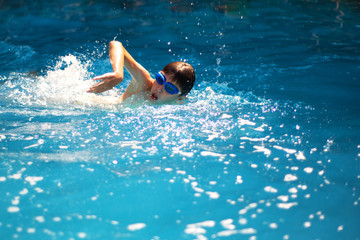 A young athletic boy swimming in an indoor pool.