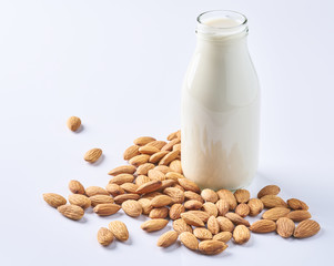 almonds and a bottle of almond milk on a white background. Vegan milk.