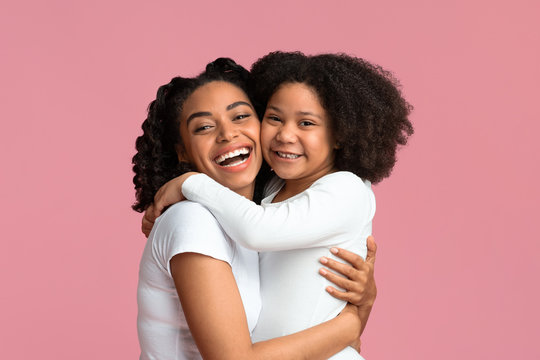 Little Black Girl Embracing Her Mother While Posing Against Pink Background