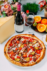 Italian pizza with cheese and beef with vegetables and tomatoes on a white background