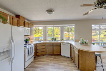 Kitchen interior with older cabinets in American classic lake front rambler house with low ceiling and hardwood floor.