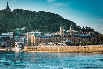 Fototapeta premium Historic center of the city of san sebastian in donostia, guipuzcoa, basque country, Spain. On the beach of La Concha with the mountain, the town hall and the port. The sky is blue and cloudless