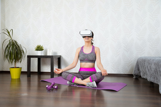 Young girl stay home in quarantine and go in for sports with virtual reality glasses. Woman exercise yoga while at home wearing virtual reality glasses - Powered by Adobe