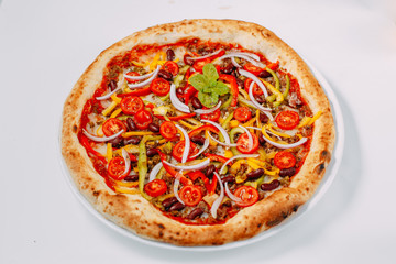 Italian pizza with cheese and beef with vegetables and tomatoes on a white background