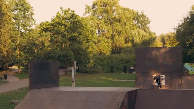 Slow motion bmx boy jumping high in the air doing no hander trick at the skatepark during golden hur. Beautiful cinematic shot with natural warm light.