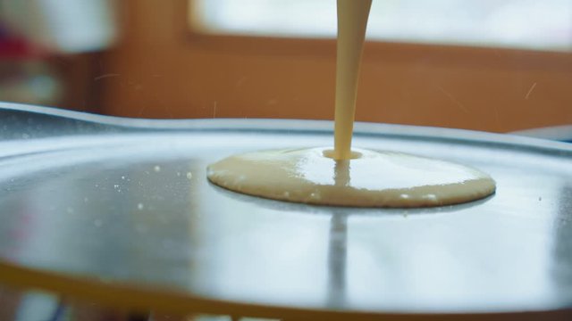 Pancake batter is poured to fry pan. Home cooking tortilla. Slow mo. Clouse up.