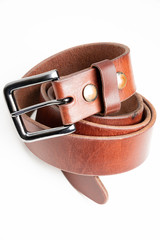 A formal studio product shot of a men’s used brown leather belt with patina set on plain white background.