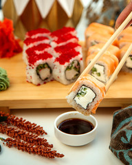 Fototapeta na wymiar sushi roll with smoke salmon cucumber and cream dipped into say sauce