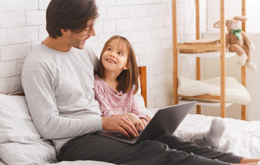 Single father teaching daughter how to use laptop