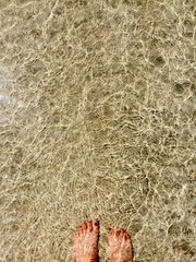 Reflection through bright sunshine into the water in the beach and the foots