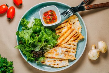quesadilla with sauce and lettuce with vegetables on a decorated table