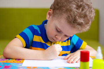 Little boy draws at the table. Child activities at home, training