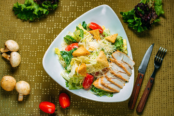 Caesar salad with chicken and vegetables on a decorated table