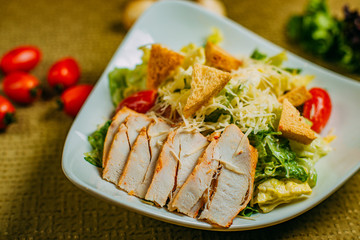 Caesar salad with chicken and vegetables on a decorated table