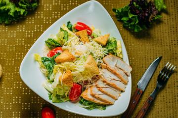 Caesar salad with chicken and vegetables on a decorated table
