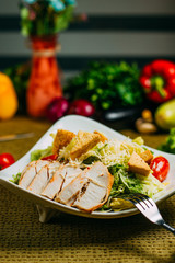 Caesar salad with chicken and vegetables on a decorated table