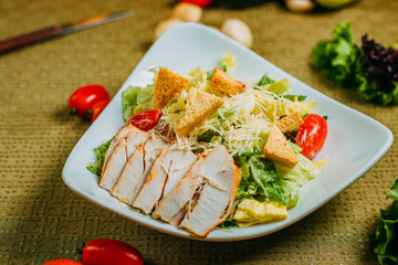Caesar salad with chicken and vegetables on a decorated table