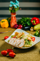 Caesar salad with chicken and vegetables on a decorated table