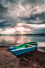 Boat on the shore of the lake under the stormy clouds