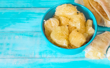pieces of pomelo in a blue bowl on the table close-up. pomelo slices in a bowl on a blue background top view.