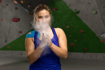 woman clap her hands with magnesium for training on a climbing wall with chalk