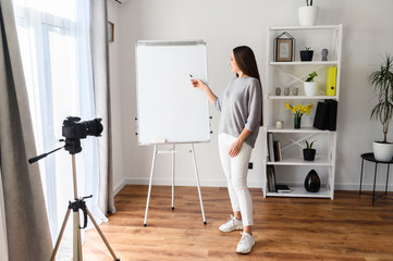 Fototapeta premium Young woman with flipchart records video lessons