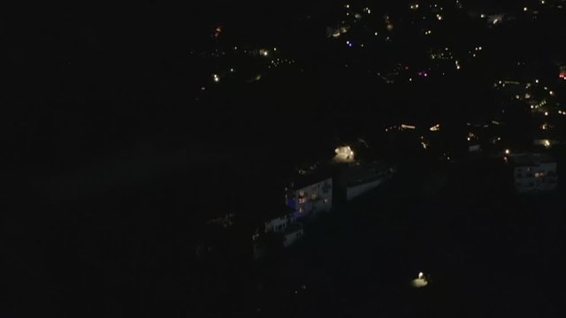 AERIAL: Slow Tilt Move over Hollywood Hills at Night revealing Los Angeles City Lights 