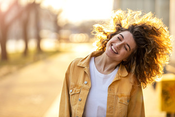 Portrait of young woman with curly hair in the city
