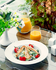 сaesar salad with chicken and a glass of orange juice