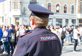 Russian police officer against the crowd at the city street. Text in russian: police