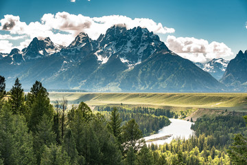 Grand Teton in the morning sun, view of snowy mountain peaks and lush greenery by the river as viewed from the snake river overlook, Grand Teton National Park, Wyoming