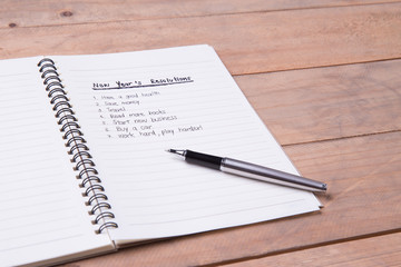 List of New Year's resolution on notepad, vintage style on wood with space for layout.