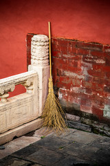 An old broom rests on the corner of a brick wall in Beijing, China.