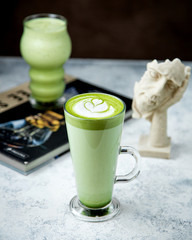 a glass of matcha green tea with latte art on top 1