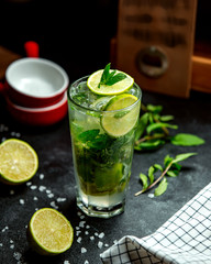 a glass of mojito drink garnished with lime and mint