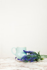 Lavender flowers and pastel blue mug on a marble table