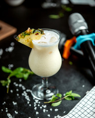 a glass of pineapple cocktail garnished with pineapple slice