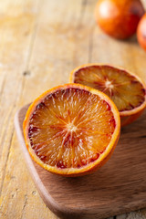 Aerial close-up of half blood oranges, with selective focus, on dark table, vertical, with copy space