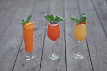 three alcoholic cocktails with fruits on an old wooden table