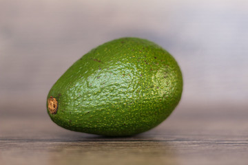 One avocado fruit on a wooden background.