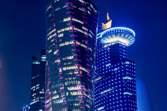Night view on the centre of the city Doha, Qatar with many modern luxury building and skyscrapers illuminated with numerous lights. Close-up shot