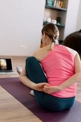 Attractive woman practicing yoga at home using online training instructions