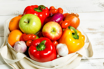 Colorful vegetables and fruits in an eco reusable bag on a white background. Healthy food, vitamins. Delivery of products. 